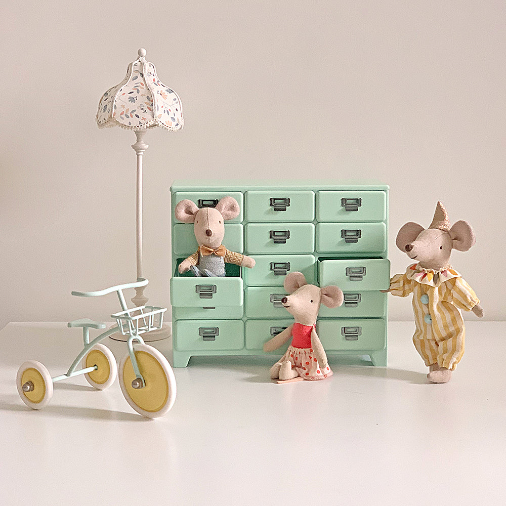 Mint miniature drawer cabinet styled with dollhouse mice, tricycle and floor lamp in a playroom scene
