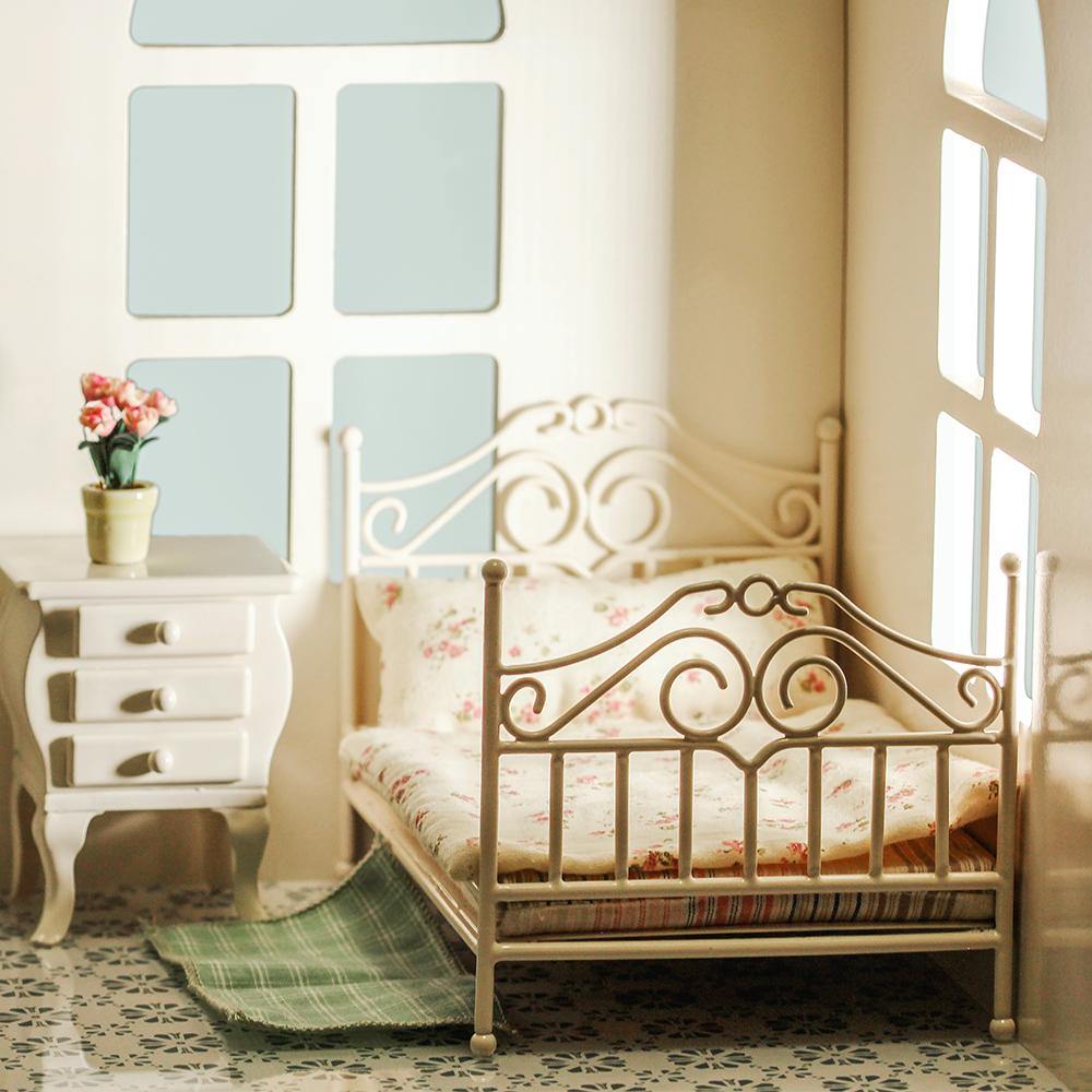 White 1:12 dollhouse bed in a soft bedroom scene with bedside cabinet, window and green rug