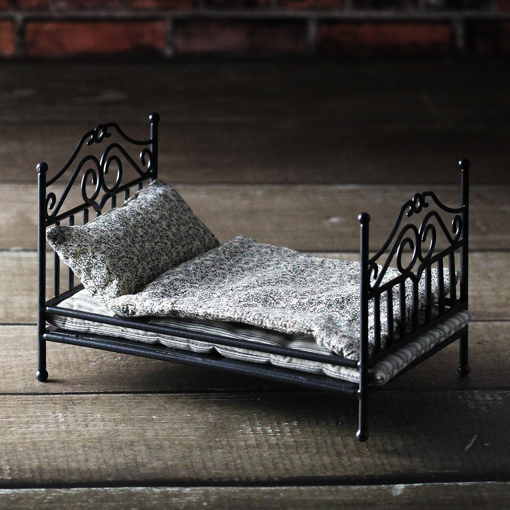 Black 1:12 scale hand-bent iron wire dollhouse antique bed with small floral bedding on wood floor