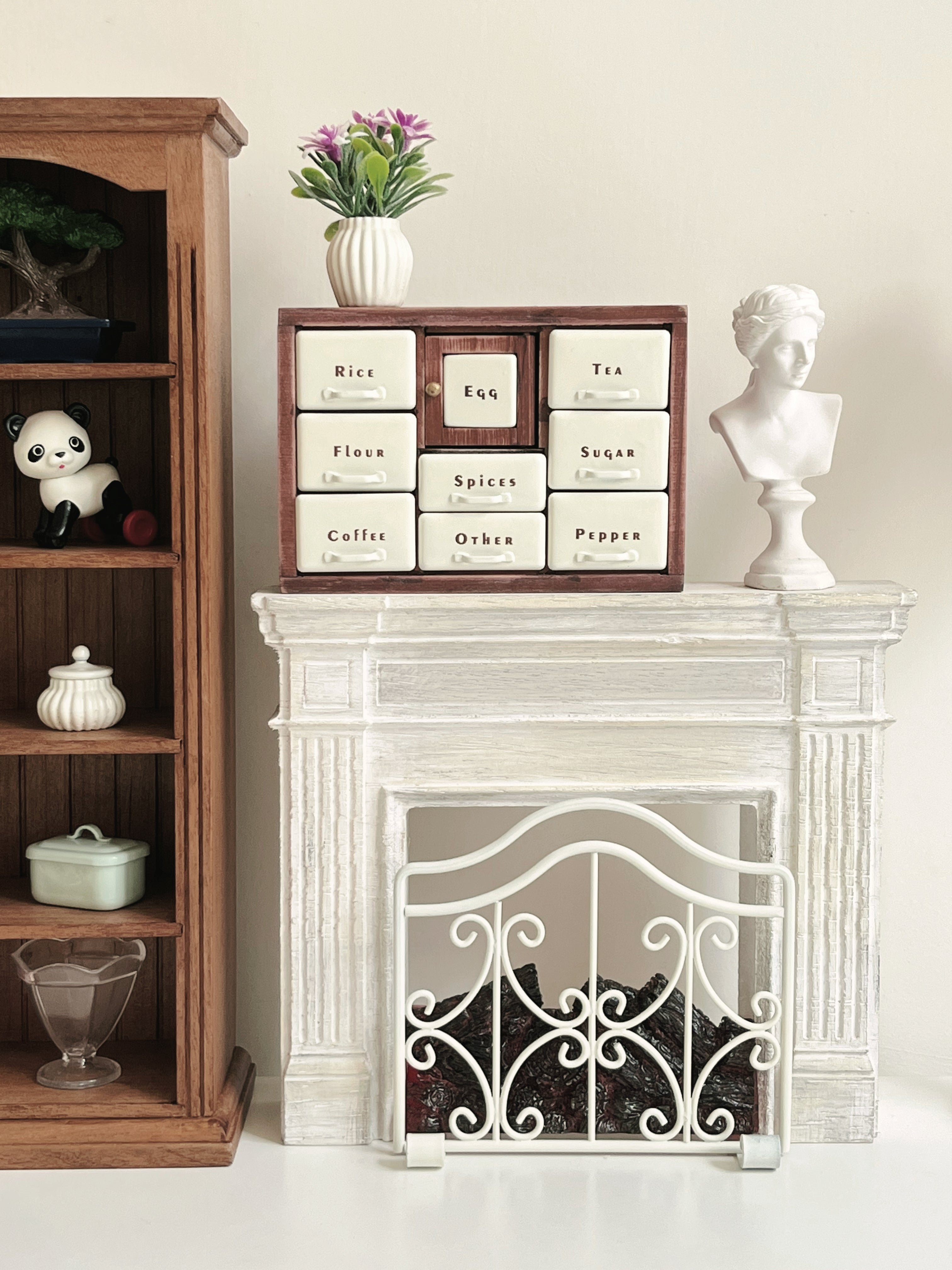Red Bean spice cabinet styled on white fireplace mantel beside dollhouse bookcase
