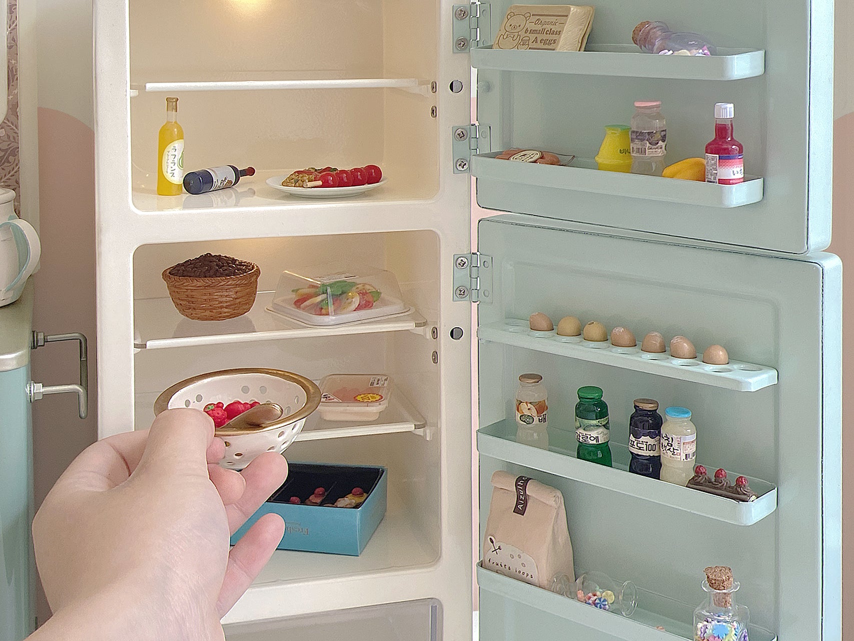 Close view of open mint green dollhouse refrigerator with lit shelves, door storage and miniature food props not included