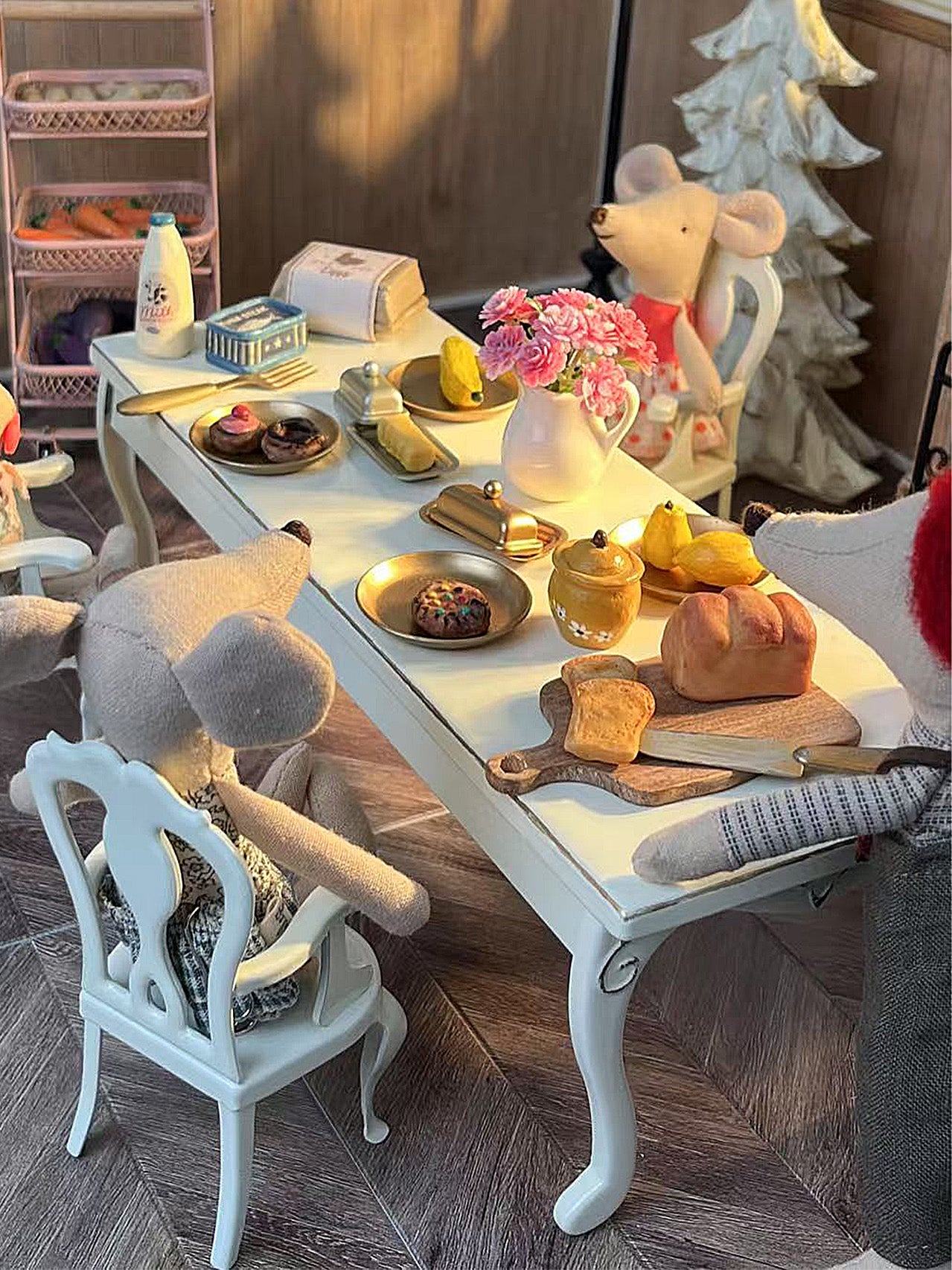 White Princess Chairs around white Retro Long Table in close-up dinner scene with bread, flowers and miniature food
