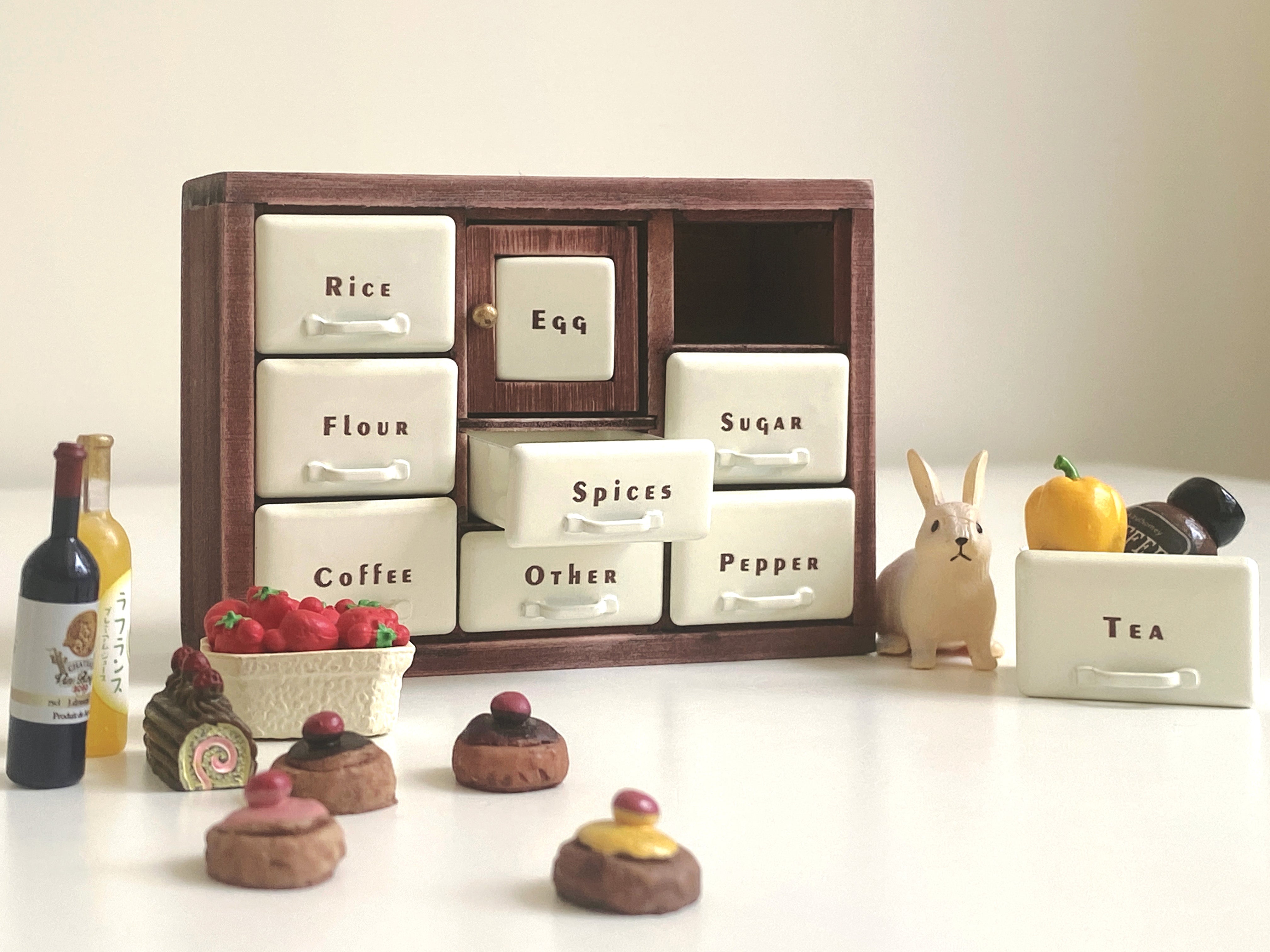 Red Bean spice cabinet with open Spices drawer beside bottles, vegetables and tiny cakes
